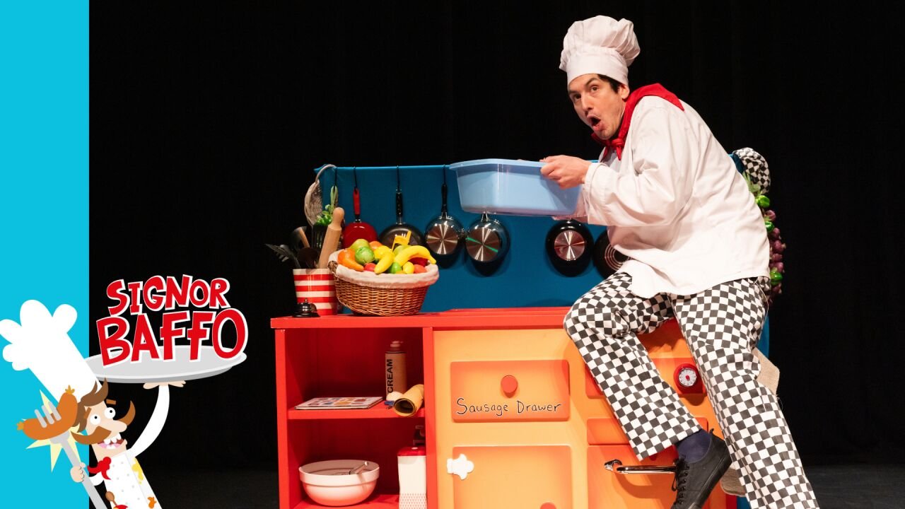 Signor Baffo in a chef costume performing silly antics on stage for a family audience